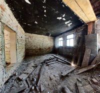 Unfinished interior of a family house with brick walls and a broken floor.