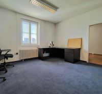 Offices with blue carpet, simply furnished, with a desk and chairs.