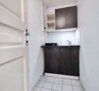 A compact kitchenette in offices with dark wood decor and white tiles.