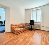 Offices with wood-patterned flooring, a sofa, a window, and a swivel chair.