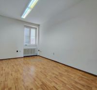 An empty office with a wooden floor and a radiator under the window.
