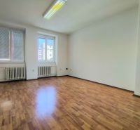 An empty office with wood-patterned flooring and large windows.