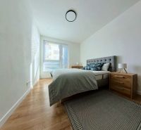 A bedroom in a 3-room apartment with a wood-patterned floor and a large window.