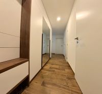 A hallway in a 3-room apartment with a wooden decor floor and white furniture.