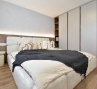 Bedroom in a 4-room apartment with a bed, built-in wardrobe, and wooden decor flooring.