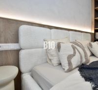 A bedroom with a headboard and shelves in a 4-room apartment, with soft lighting.