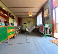 The interior of the cabin with simple furniture, a kitchenette, and a sink.