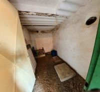 A narrow basement space in a cottage with a stone floor and white walls.