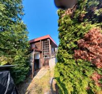 A cottage in Štitáre on Pri Kaplnke street surrounded by trees and a blue sky.
