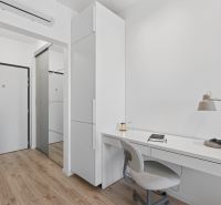 A simple white workspace with a desk, chair, and floor with a wood decor.