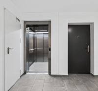 Studio apartment entrance hall with a lift and staircase, bright surroundings and neutral colors.