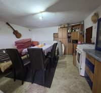 The interior of a cottage with a kitchen area, table, and chairs, a simple and cozy space.