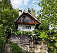 A cottage in Banská Bystrica surrounded by greenery with wooden elements and a balcony.