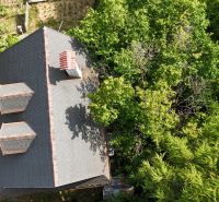 The roof of a cottage in Banská Bystrica surrounded by dense greenery, view from above.