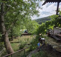 A cottage in a picturesque setting near Banská Bystrica, surrounded by lush greenery and trees.