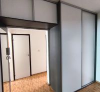 A hallway in a 3-room apartment with sliding wardrobes and a floor with a wooden decor.
