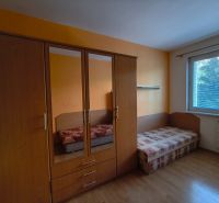 A room with a wooden floor decor, a wardrobe, and a bed in a 3-room apartment.