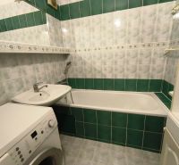 A bathroom with green and white tiles, a bathtub, and a washing machine, a 3-room apartment.