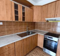 A kitchen with wooden cabinets in a 3-room apartment, flooring with a wooden decor.