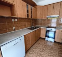A kitchen with wooden decor in a 3-room apartment, equipped with appliances and cabinets.