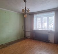 A room with a wooden floor decor, a window with a radiator, a light wall, a family house.