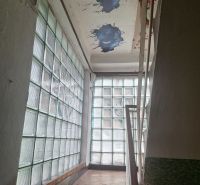 A staircase in a family house with a glass wall and a damaged ceiling.