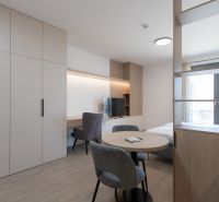 1-room apartment with wood-patterned flooring, wardrobes, a table, chairs, and a window.