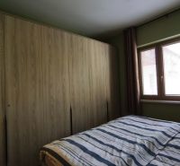 Bedroom in a 2-room apartment with a large wardrobe and a window with blinds.