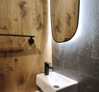 Bathroom with wood-patterned flooring, a mirror, and a small sink in a 2-room apartment.