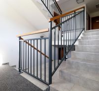 Staircase in a holiday apartment with tiles, railing, and carpet.