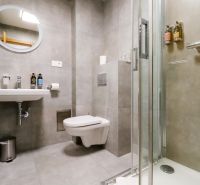 The bathroom of a holiday apartment with a sink, shower, and mirror.