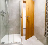 Bathroom in a holiday apartment with tiled walls and a shower corner.