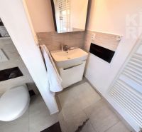 Bathroom in a 2-room apartment with a sink, mirror, and wall-hung toilet.