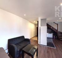 Living room of a 2-room apartment with a sofa, a table, and a staircase. Floor with wood decor.