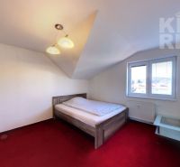 Bedroom in a two-room apartment with a simple bed and a red carpet.