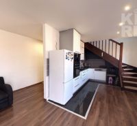 A kitchenette in a 2-room apartment with a wood-patterned floor and a sofa.
