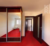 Interior of a 2-room apartment with a red carpet and a built-in wardrobe with a mirror.