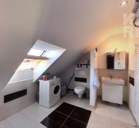 A bathroom under the roof in a 2-room apartment with a washing machine and a toilet.