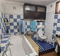 A bathroom with a bathtub, blue tiles, and a wooden decor floor in a 3-room apartment.