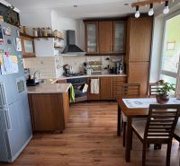 A kitchen in a 3-room apartment with a wood-decor floor and wooden furniture.