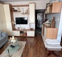Living room with wood-patterned flooring in a 3-room apartment, cozy interior with decorations.