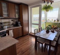 A kitchen in a 3-room apartment with a wood-patterned floor and a dining table.