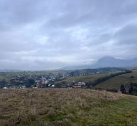 Panorama of agricultural and forest lands in Stránske with a view of the village and mountains.
