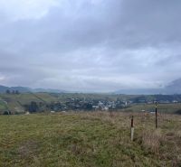 The landscape of agricultural and forest lands near Stránske with a rising mountain panorama.