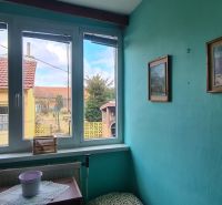 Interior of a family house with coats on a hanger, green walls, and a view from the window.