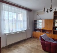 Living room with an armchair, shelves, and a wooden decor floor in a family house.