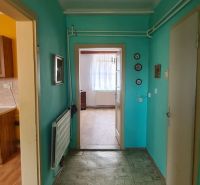 A hallway in a family house with turquoise walls and linoleum flooring.