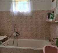 Bathroom with a bathtub, sink, and small window in a family house.