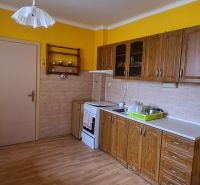 A kitchen in a family house with wooden decor, yellow walls, and a dining table.