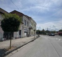 Hlavné námestie Street in Šahy, commercial spaces by the road, with a sidewalk and trees.